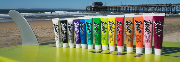 Row of Zinka sunscreen tubes on a table with a beach and pier in the background Zinka sunscreen Zinka Nose Coat Waterproof Sunblock 0.6oz Sunscreen surferswarehouse.myshopify.com